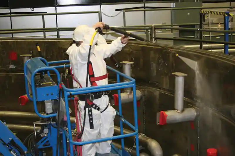 BELFOR Environmental technician power washes and decontaminates manufacturing facility
